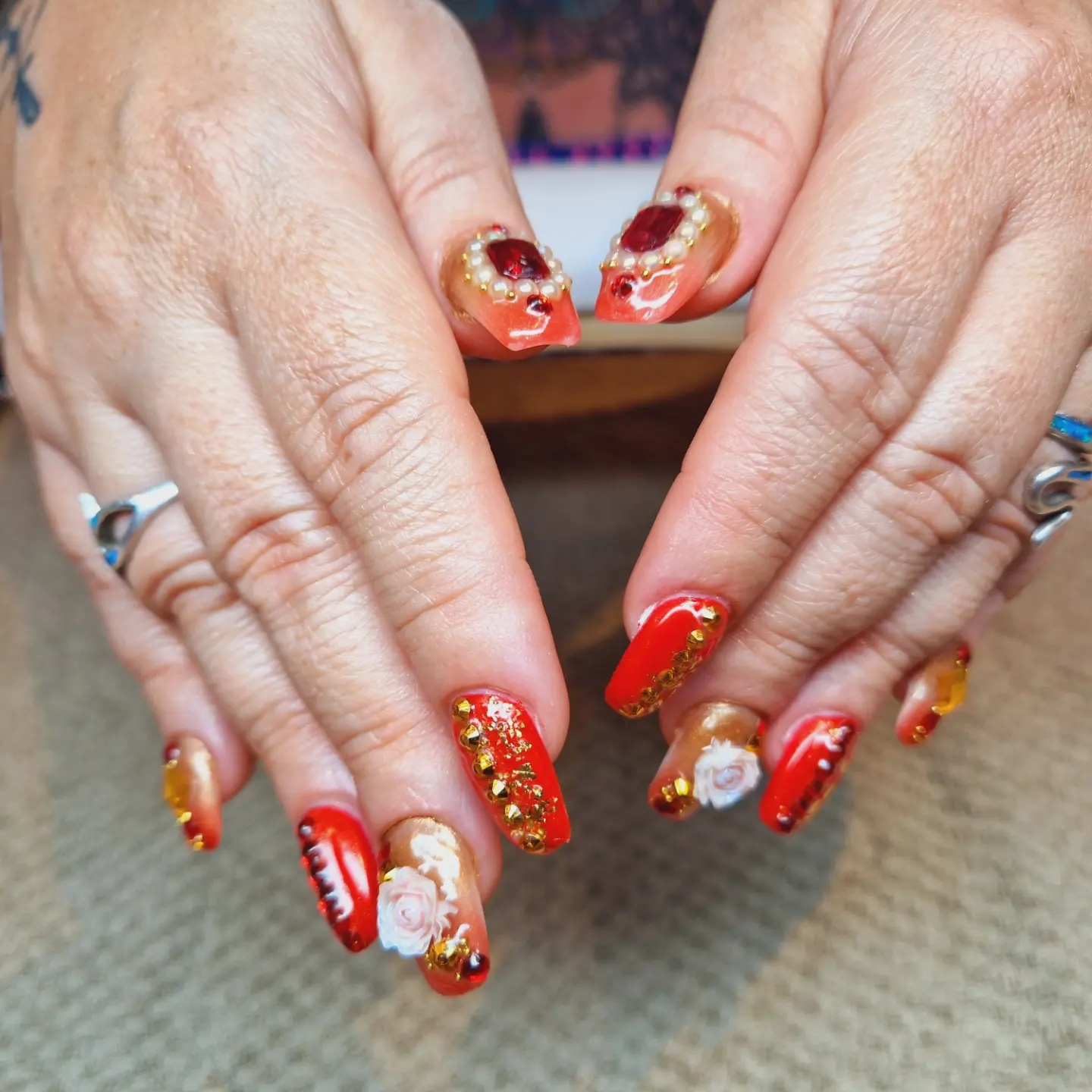 Red and gold nails with sculpted roses and gem details